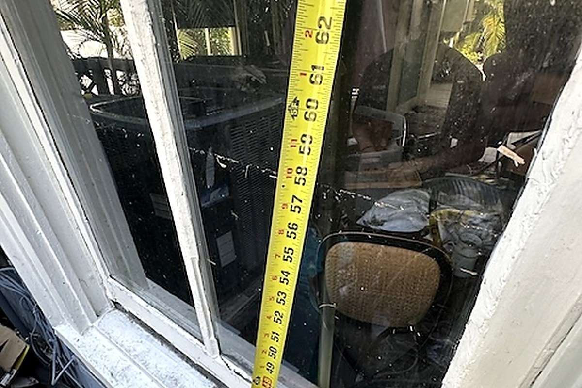 A tape measure running up a window frame, reading sixty-four inches at the flood water line.